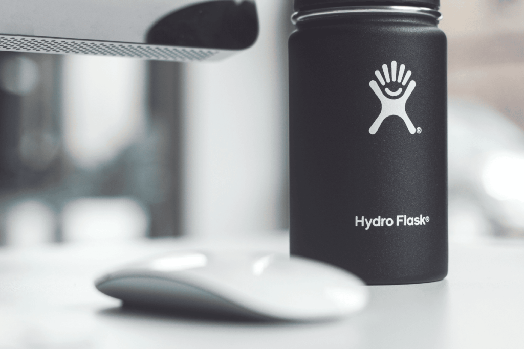 A photo of a black hydro flask next to a computer mouse. Very stylish photography