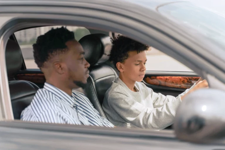 a dad teaching his teenage son how to drive.