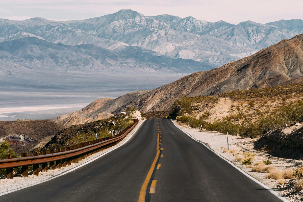 a photo of a highway in the desert with mountains in the background. Symbolizing "The Open Road"